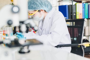 Asyalı bilim adamları laboratuvarda test ve analiz için kimyasallar hazırlıyorlar. Bilim adamları cam ve beyaz gömlekleri temizliyorlar. Bilim ve Kimya Konsepti