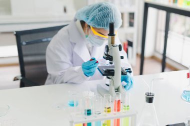 Asyalı bilim adamları laboratuvar testleri ve analizleri için bir mikroskop hazırlıyorlar. Bilim ve Kimyasal Konseptler.