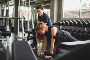 Spor eğitmeni genç bayan sporcuların eğitimini kontrol ediyor. Spor salonu konseptinde atlet fitness egzersizleri.