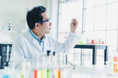 Asyalı bilim adamları laboratuarda test ve analiz için bitki bazlı materyaller hazırlıyorlar. Bilim adamları cam ve beyaz gömlekleri temizliyorlar. Bilim ve Kimya Konsepti