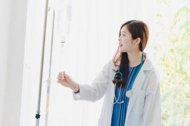 Asyalı kadın doktor hastane yatağında yatan hastayı ziyaret ediyor..