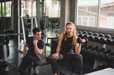 Spor eğitmeni genç bayan sporcuların eğitimini kontrol ediyor. Spor salonu konseptinde atlet fitness egzersizleri.