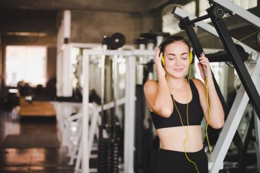 Güzel kadınlar spor salonuna egzersiz yapmaya gelir ve kulaklıklardan müzik dinleyerek rahatlarlar. Spor giyer..