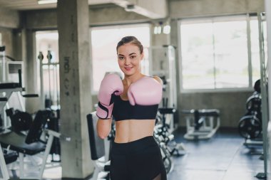 Güzel kızlar spor salonunda boks yaparak egzersiz yaparlar. Pembe bir boks eldiveni giyiyor ve egzersiz yapıyor..