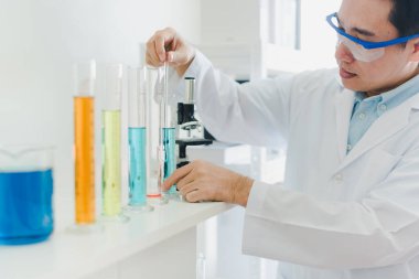 Asyalı bilim adamları laboratuvarda test ve analiz için kimyasallar hazırlıyorlar. Bilim adamları cam ve beyaz gömlekleri temizliyorlar. Bilim ve Kimya Konsepti