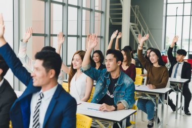 Asyalı erkek konuşmacı seminerlerde ve atölyelerde toplantıdaki insanlarla konuşuyor. Toplantıya katılanlar soru sormak için ellerini kaldırdılar..