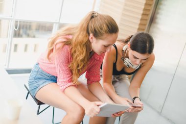 Telefon ve tablet oynayan iki güzel genç kadın. rahatlama konsepti.