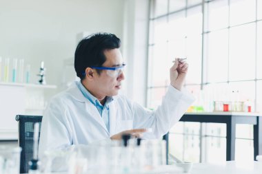 Asyalı bilim adamları laboratuarda test ve analiz için bitki bazlı materyaller hazırlıyorlar. Bilim adamları cam ve beyaz gömlekleri temizliyorlar. Bilim ve Kimya Konsepti