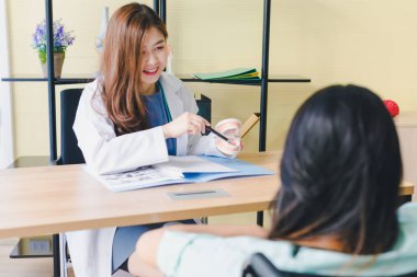 Asyalı güzel kadın dişçi hastanın dişlerinin ağrısını analiz eder ve açıklar..