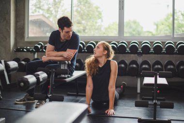 Spor eğitmeni genç bayan sporcuların eğitimini kontrol ediyor. Spor salonu konseptinde atlet fitness egzersizleri.