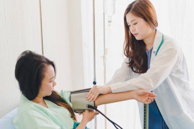 Asyalı kadın doktorlar hastanın basıncını ölçmeye geliyor. Hastanın yatağında yatıyor..