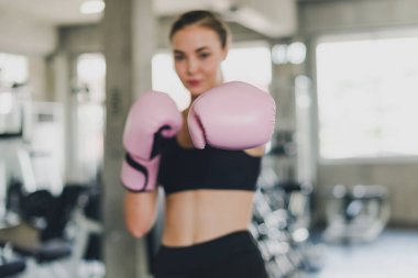 Güzel kızlar spor salonunda boks yaparak egzersiz yaparlar. Pembe bir boks eldiveni giyiyor ve egzersiz yapıyor. Boks eldivenlerine odaklan..