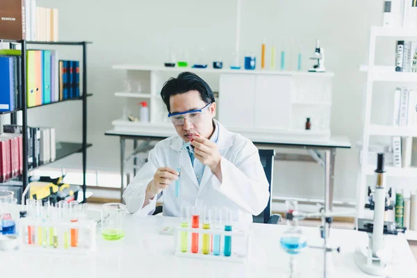 Asian scientists are preparing chemicals for testing and analysis in the laboratory. Scientists clear glasses and white shirts. Science and Chemistry Concept