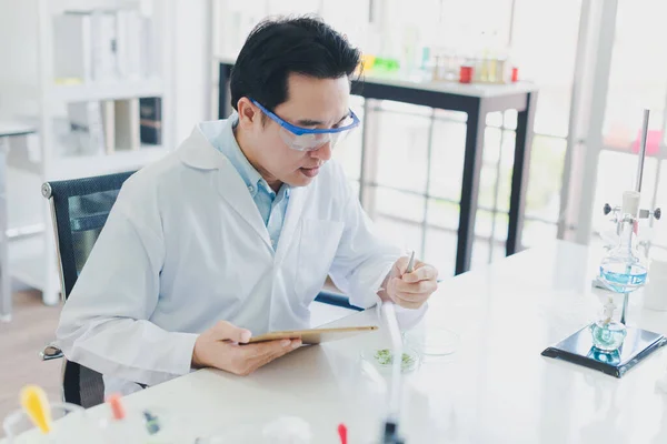 Asian scientists are preparing chemicals for testing and analysis in the laboratory. Scientists clear glasses and white shirts. Science and Chemistry Concept