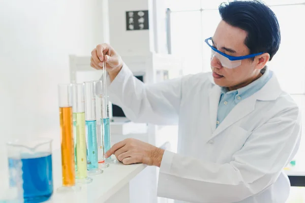 Asian scientists are preparing chemicals for testing and analysis in the laboratory. Scientists clear glasses and white shirts. Science and Chemistry Concept