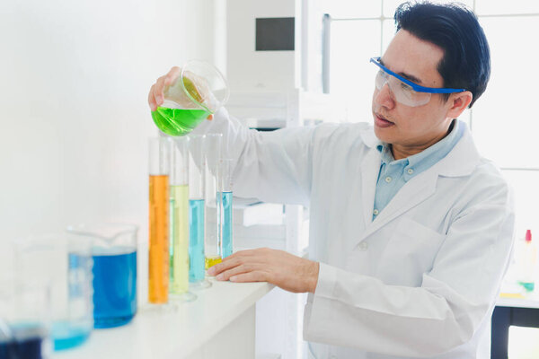 Asian scientists are preparing chemicals for testing and analysis in the laboratory. Scientists clear glasses and white shirts. Science and Chemistry Concept