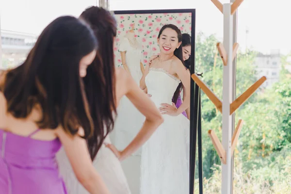 Mooie Bruid Probeer Een Witte Trouwjurk Voor Spiegel Met Bruidsmeisjes — Stockfoto