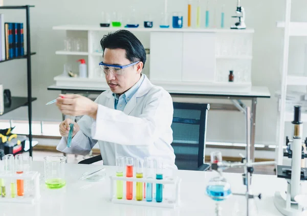 Asian scientists are preparing chemicals for testing and analysis in the laboratory. Scientists clear glasses and white shirts. Science and Chemistry Concept