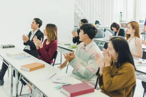 Asians attend seminars and listen to lectures from speakers in the training room. Some people take notes. Some people raised their hands to ask the narrator. And applauded when the speaker finished speaking.