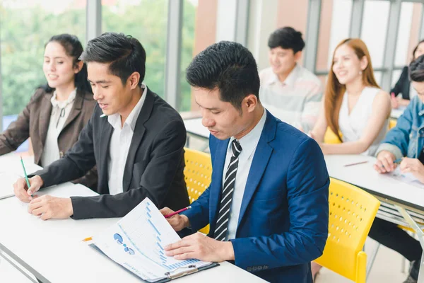 Asian male speaker is speaking at seminars and workshops to the people in the meeting.