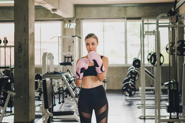 Beautiful girls exercise by boxing in the gym. She wears a pink boxing glove and wears exercise.