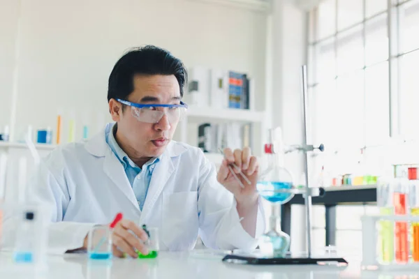 Asian scientists are preparing chemicals for testing and analysis in the laboratory. Scientists clear glasses and white shirts. Science and Chemistry Concept