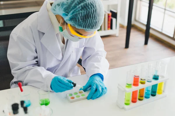 Asyalı bilim adamları laboratuvarda test ve analiz için kimyasallar hazırlıyorlar. Bilim adamları cam ve beyaz gömlekleri temizliyorlar. Bilim ve Kimya Konsepti