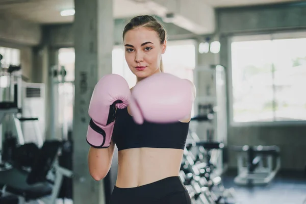 Beautiful girls exercise by boxing in the gym. She wears a pink boxing glove and wears exercise.