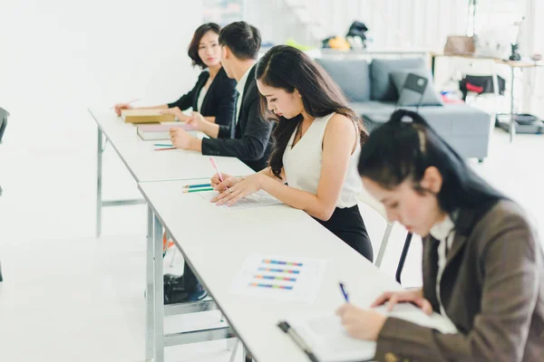 Asians attend seminars and listen to lectures from speakers in the training room. Some people take notes. Some people raised their hands to ask the narrator. And applauded when the speaker finished speaking.