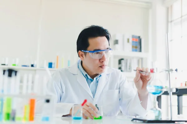 Asian scientists are preparing chemicals for testing and analysis in the laboratory. Scientists clear glasses and white shirts. Science and Chemistry Concept