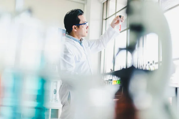 Asian scientists are preparing chemicals for testing and analysis in the laboratory. Scientists clear glasses and white shirts. Science and Chemistry Concept