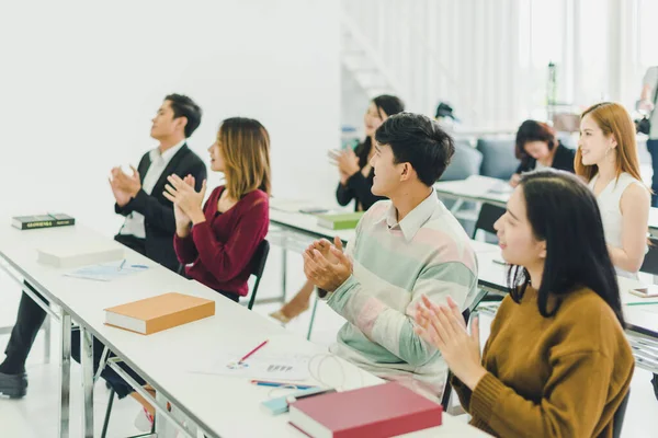 Asians attend seminars and listen to lectures from speakers in the training room. Some people take notes. Some people raised their hands to ask the narrator. And applauded when the speaker finished speaking.