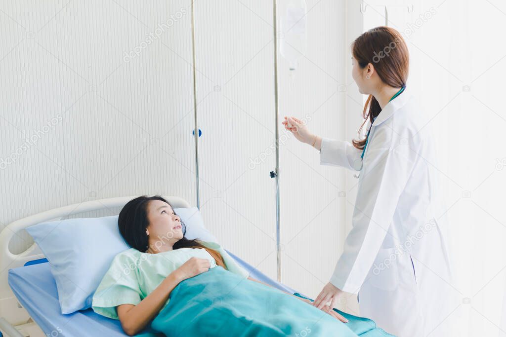 Asian woman doctor visits the patient lying in the hospital bed.
