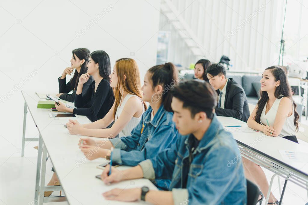 Asians attend seminars and listen to lectures from speakers in the training room. Some people take notes. Some people raised their hands to ask the narrator. And applauded when the speaker finished speaking.