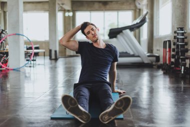 Spor salonunda yoga minderleri üzerinde egzersiz yapmadan önce esneme hareketleri yapan atletik erkekler. Boyun kaslarını esneterek..