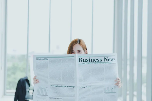Beautiful Asian business women are reading business newspapers in the meeting room of the workplace.