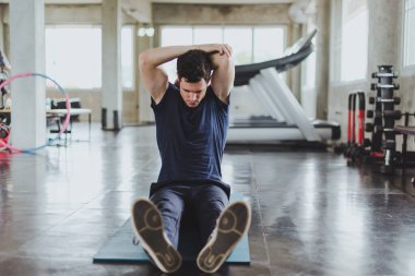 Spor salonunda yoga minderleri üzerinde egzersiz yapmadan önce esneme hareketleri yapan atletik erkekler. Kolları kasılmış..