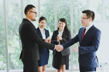 İstatistiksel grafik olarak sunum için Asyalı şirket toplantıları. İş adamlarından oluşan bir ekip, başarılı bir iş anlaşmasından sonra el sıkışıyor..