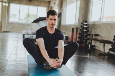 Spor salonunda yoga minderleri üzerinde egzersiz yapmadan önce esneme hareketleri yapan atletik erkekler..