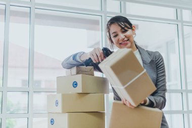 Evde çalışan güzel bir iş kadını müşterilerine teslim edilecek ürün miktarını kontrol ediyor..