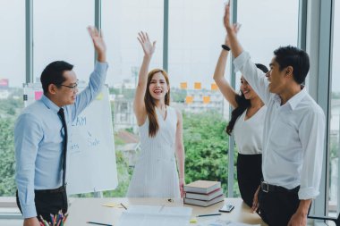 Asyalı takım arkadaşları grafikleri ve iş gazetelerini tartışmak için toplanıyorlar. Toplantı bittiği için herkes memnun..