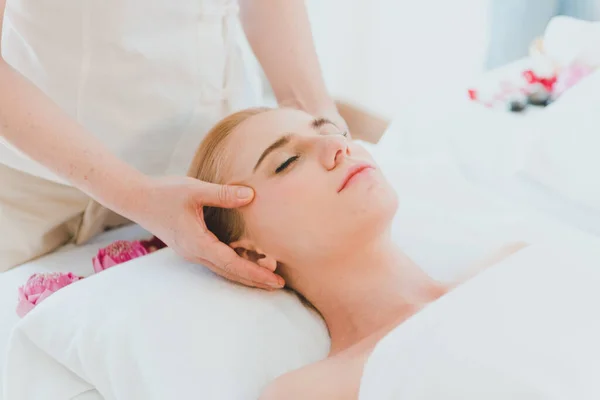 Beautiful woman lying on the bed for a spa asia massage at luxury spa and relaxation. The masseuse massaged her face and head in the spa room.