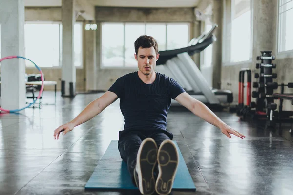 Spor salonunda yoga minderleri üzerinde egzersiz yapmadan önce esneme hareketleri yapan atletik erkekler. Kolları kasılmış..