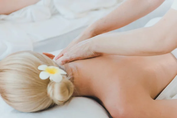 Beautiful woman lying on the bed for a spa asia massage at luxury spa and relaxation. The masseuse is massaging her arms and shoulders into the spa room.