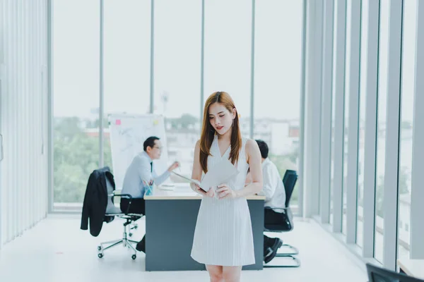 Beautiful Asian business women are reading business newspapers in the meeting room of the workplace.