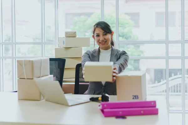 A beautiful businesswoman working at home is checking orders for products to be delivered to her customers from notebooks.