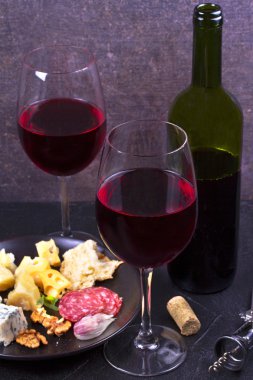 Kırmızı gözlük ve şişe şarap ile fındık, peynir ve salam
