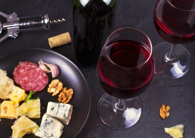 Kırmızı gözlük ve şişe şarap ile fındık, peynir ve salam