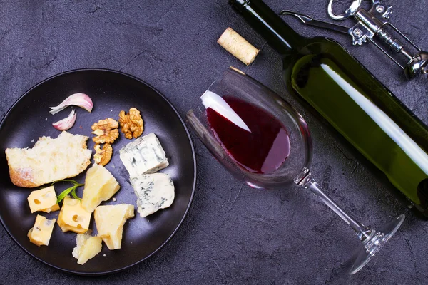 Copos vermelhos e garrafa de vinho com nozes, queijo e salame — Fotografia de Stock