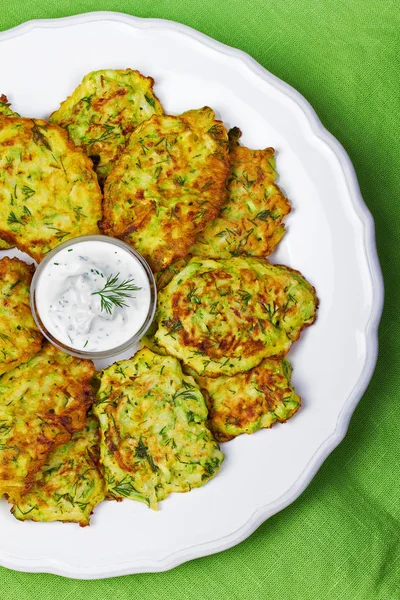 Zucchini Pancakes With  Sour Cream in White Plate.